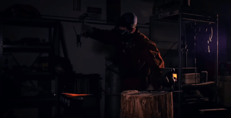 Someone hitting red hot metal with a hammer in a forge.